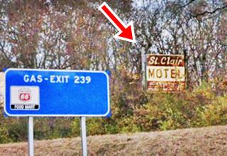 motel neon sign hidden by trees next to the freeway