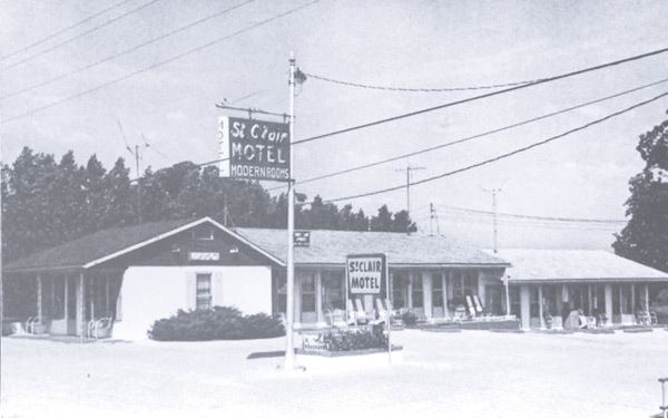 black and white postcard motel with neon sign and gable roof