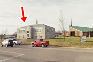 Route 66 and behind, a Catholic school and church, and lawn