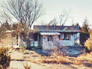 Route 66 Tavern in Hazelgreen MO wood frame building in ruins with trees growing around it