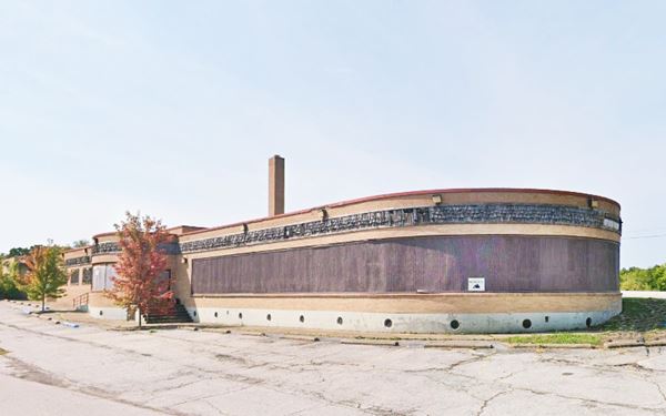 long, one-story flat roof building with large boarded window, and rounded tip, vacant seen from Route 66