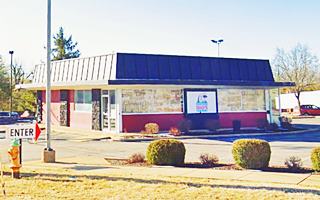 Former Tobey’s Drive In flat roofed square building with parking lot around it