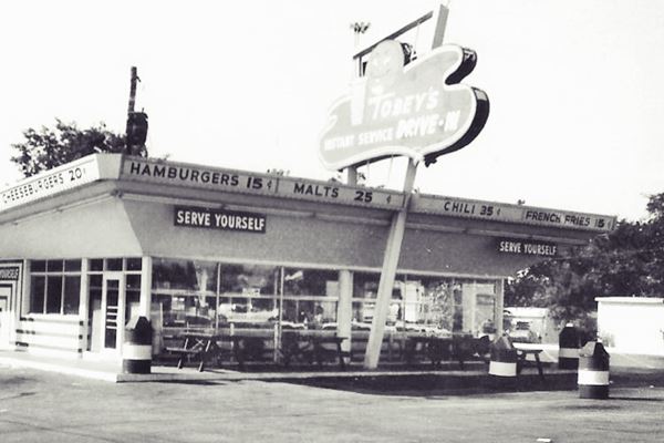 black and white 1960s photo box-shaped, flat roof burger diner with neon sign