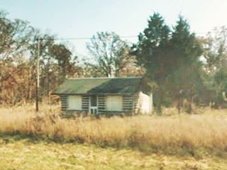 log cabin with gable roof in a meadow by the forest