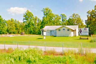 gable roof building in a field by highway