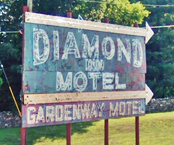 neon sign in red, green and yellow with words "Diamond Inn motel Gardenway motel" with arrows pointing towards a Route 66 motel