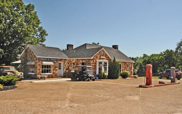 hipped roof, stone building with gas pumps and vintage car. The Historic Wagon Wheel Motel