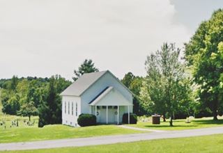 hW woodframe chapel in a meadow with trees
