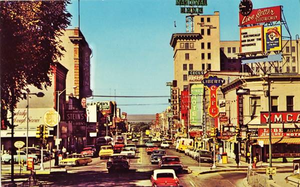West Central and 1st St. ABQ 1950s view color postcard with 1950s cars along Central Ave, neon signs, people, buildings, hotels, busy morning view