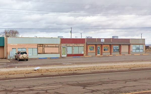 long line of buildings facades with windows, flat roofs, and parking area in front of them, former cafe and gas station, seen from Route 66