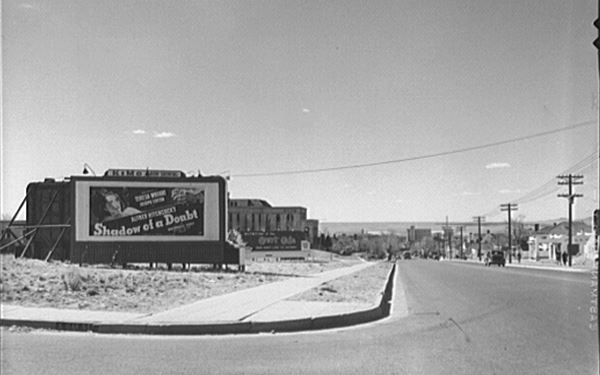 black and white photo, buildings in the distance, highway to the right, gas station beyond. Movie sign to the left, Hospital and underpass in the distance