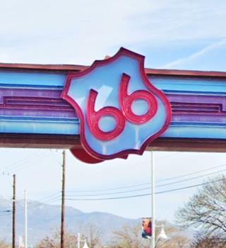 detail of a route 66 shield in red and white on an arch, Sandia mountains in the d.istance