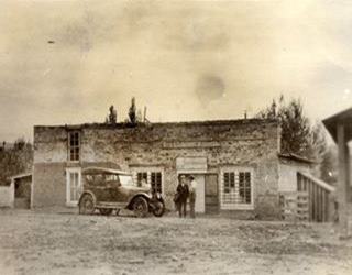 1918 Gross Kelly and Co. store in Pecos Route 66 black and white 1918, car, two men and long adobe single story store Gross Kelly and CO
