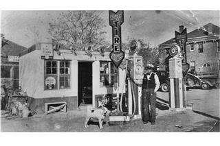 Hanging Tree Los Lunas black and white, 1920s, man, dog, block shaped small building with gas pumps, to the right County Courthouse