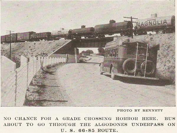 black and white, bus on Route 66 and 85 about to pass under a cargo train using an underpass