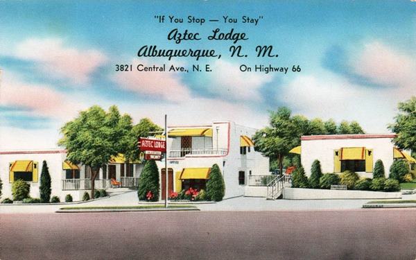 Vintage 1940s postcard color postcard trees, pueblo-style motel with central red neon sign by 2 story office