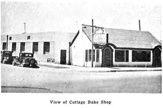 1937 view of Cottage Bakery black and white photo, cars on a side street and neon sign to the left, Route 66 in front and cottage facing it