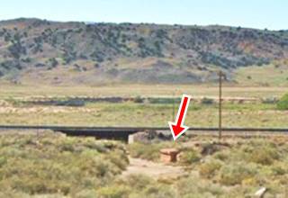 Bridge on old US66 Los Lunas stone abutement by dry creek railroad behind, shrubs, sand, hills beyond. Color, 2023