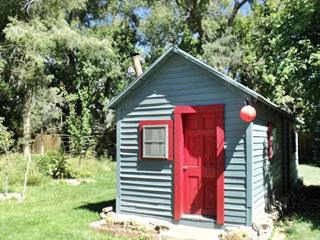 cabin in Pecos NM gable roof woodframe cabin, green and red, trees, lawn