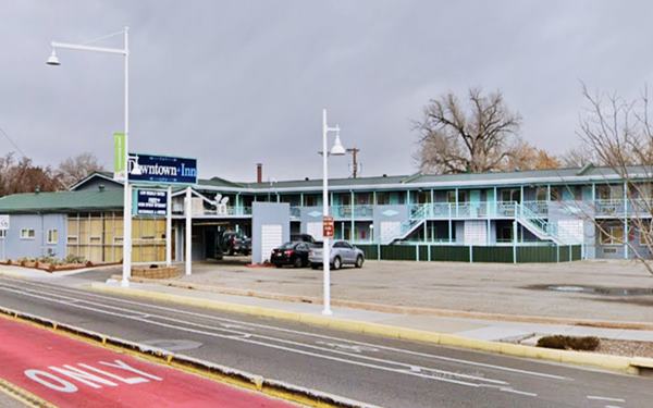 two story, L-shaped layout gable roof corner motel with neon sign
