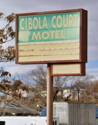 faded box shaped green sign with white letters spelling CIBOLA MOTEL seen from Route 66