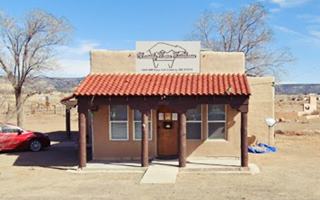 Old Cubero Cafe 2023 block shaped, flat roof, tall parapet with sign and Spanish tiled front porch with wood posts