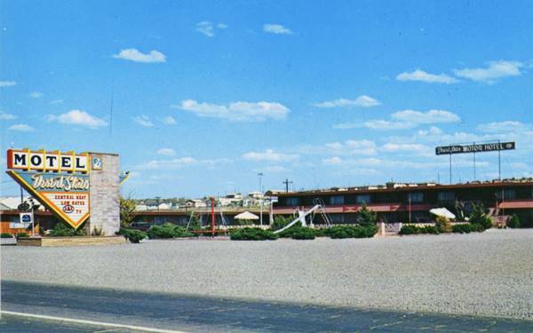 color postcard, triangular neon sign faces Rt. 66 and motel units 2 stories, surround it, courtyard with sunshades and playground c.1960s