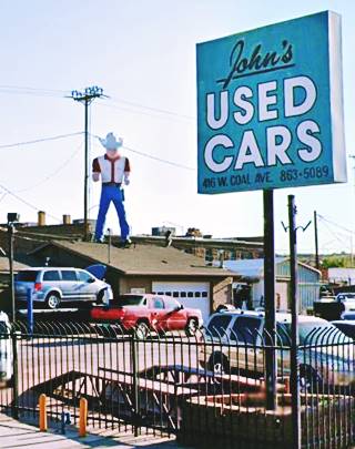 Muffler Man with hat on top of car dealer roof
