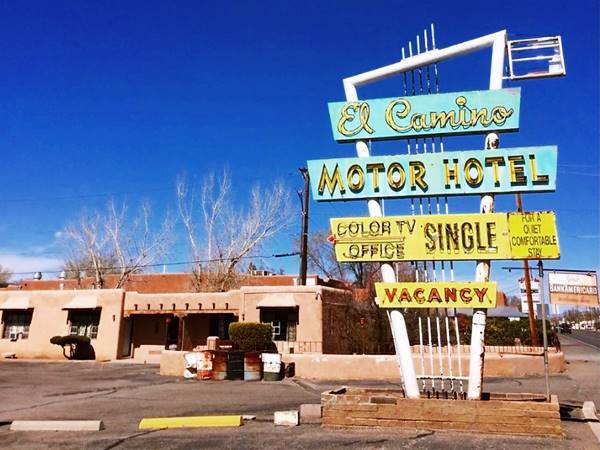 vintage neon sign word EL CAMINO MOTOR HOTEL in yellow letters accross a pair of pale blue rectangle in a triangular frame