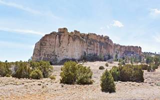 large bluff, with steep sandstone walls, sparse junipers surround it