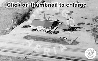 black and white view gable roof gas station, cars and canopy and US66 passing in front of it
