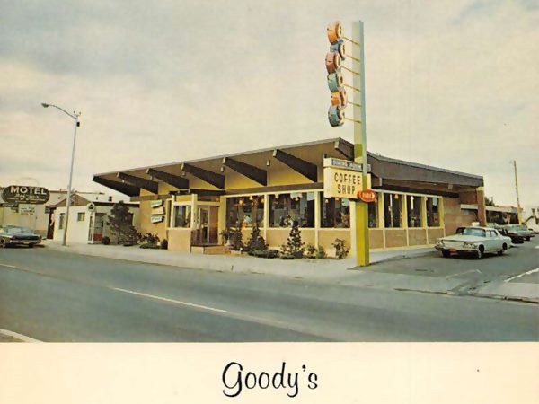 1960 color postcard of a single floor restaurant with slanted roof edges with eaves, neon sign, car on the right, windows facing Route 66