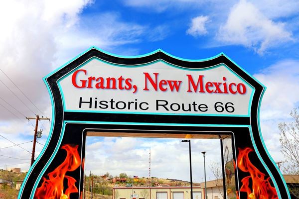color view of the upper part of a drive thru arch shaped like a US highway shield with opening to allow cars through with words: GRANTS NEW MEXICO - HISTORIC ROUTE 66 on it