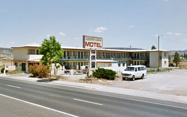 two story L shaped motel with neon sign and swimming pool seen from Route 66