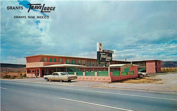 two story L shaped motel with neon sign and swimming pool seen from Route 66, car parked on highway c.1960s