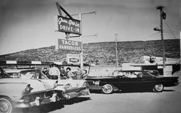 Green Goose Drive In 1961 black and white text and image advertisement: cars parked under a neon sign, hill in the distance, taken in 1961