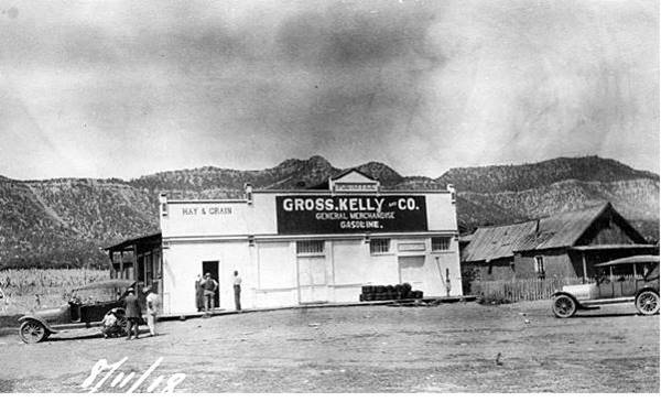 Gross Kelly and Co Store in 1918, Rowe NM Black and white, 1918, store, sells gas, two cars, In front of the store a group is fixing a flat tire