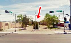 empty lot between two buildings, trees and a car parked, steel pole of an empty sign, Route 66 in front
