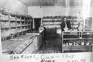 1940 view Acoma Curio Shop San Fidel US66 NM black and white interior of a trading post, man behind counter,shelves with handicrafts