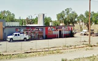 low flat roof buildings, vertical extension on roof, gas pump island vacant, a radiator repair shop