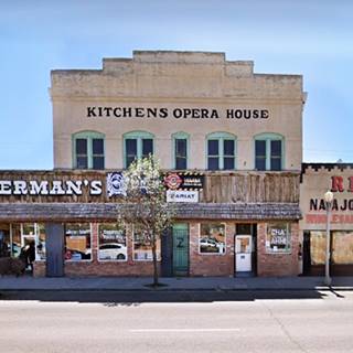 2 story stucco faced building, an opera house, windows, stepped parapet words KITCHENS OPERA HOUSE written on it