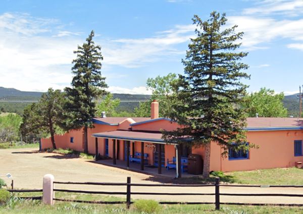 2023 Koslowski ranch view color, a pink colored adobe ranch, trees. Hills with forests