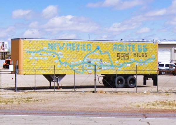 License Plate Memorial Wall, US66 Moriarty semi-trailer parked by US66, covered in yellow license plates with green and black ones marking US66 alignment and towns across New Mexico