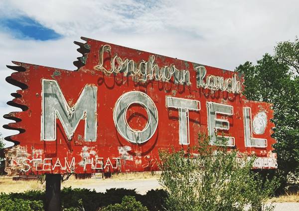 Longhorn Ranch Motel neon sign motel neon sign, red and white sign some bushes surround it