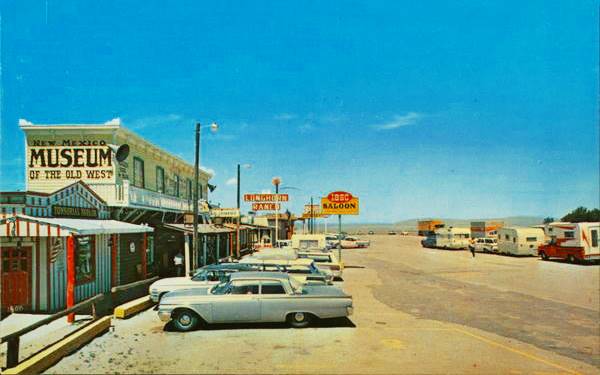 Longhorn Ranch postcard c.1960, US66 Moriarty left: cars parked facing fake Far West buildings, neon signs, Route 66 running across the page top to bottom in a color 1960s postcard