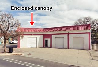 Magnolia on South 4th nowadays ABQ white building on a corner 2 service bays, tiles decorate lower part of parapet. Enclosed flat roof Canopy, former Magnolia station. Route 66 runs left to right, side street to the left