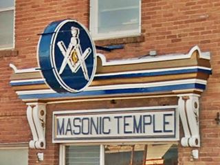 Masonic symbol neon sign on red brick building