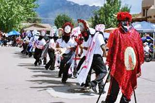Matachines dancing color, group of dancers dancing in line in colorful attires, Sandia Mountains behind