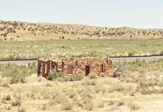 old stone building west of Mentmore on old US66 vacant roofless stone building in an field hills beyond, railroad behind