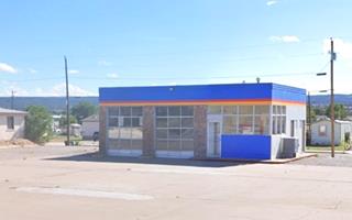 icebox shaped gas station, 2 service bays left, plate glass office right, painted red, white and blue